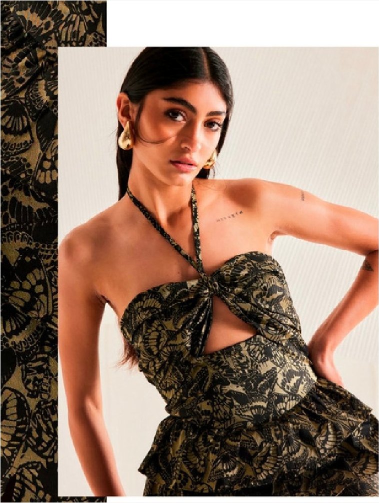 Modelo con vestido de brocado negro y dorado con recorte frontal.