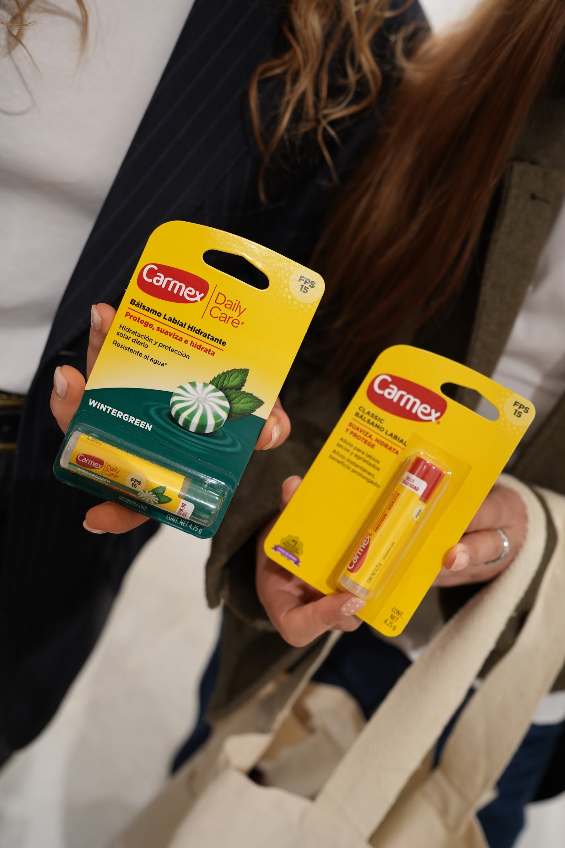 Invitada sosteniendo dos productos Carmex de la estación de cuidado.