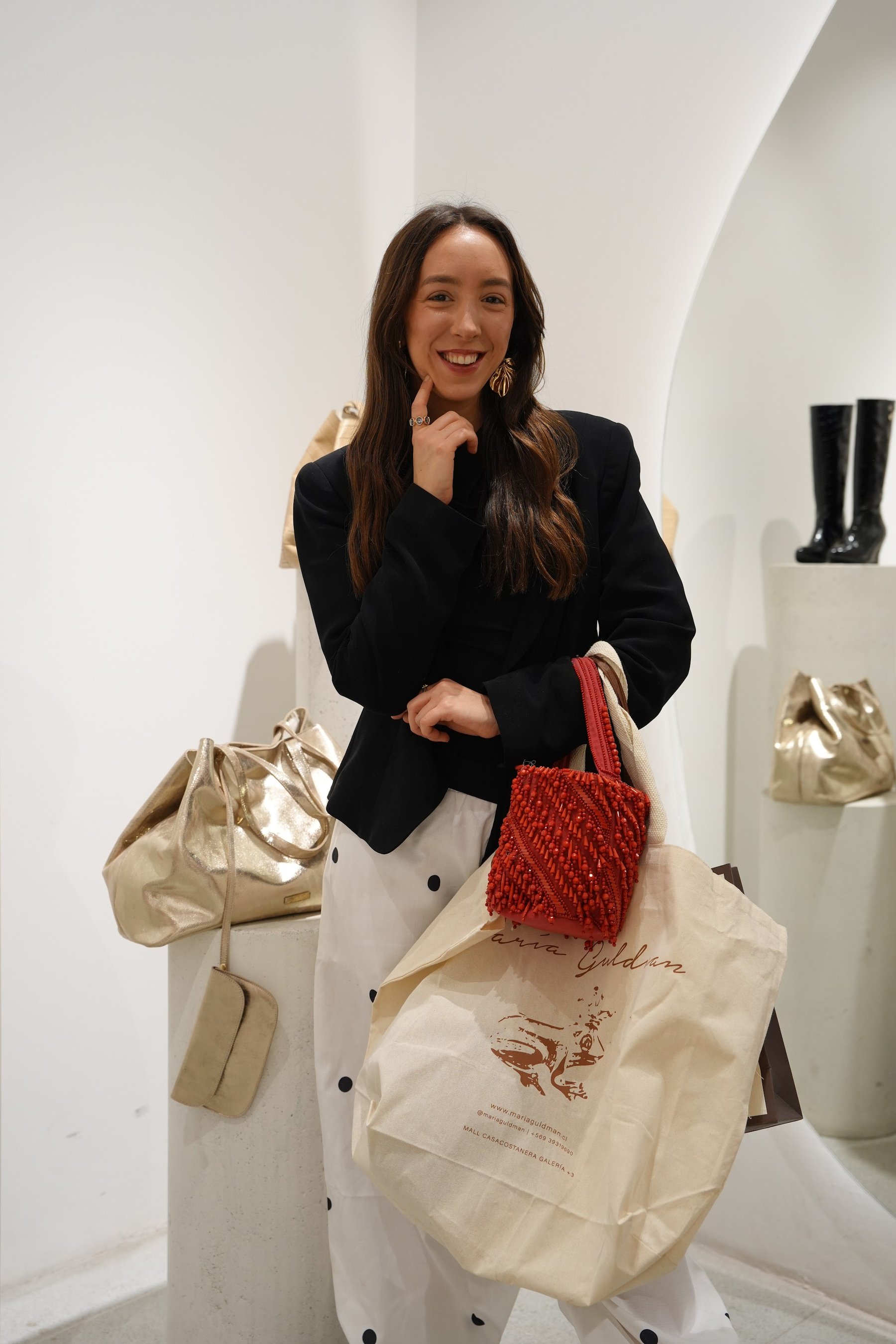 Invitada sonriendo junto a los bolsos expuestos en la sala.