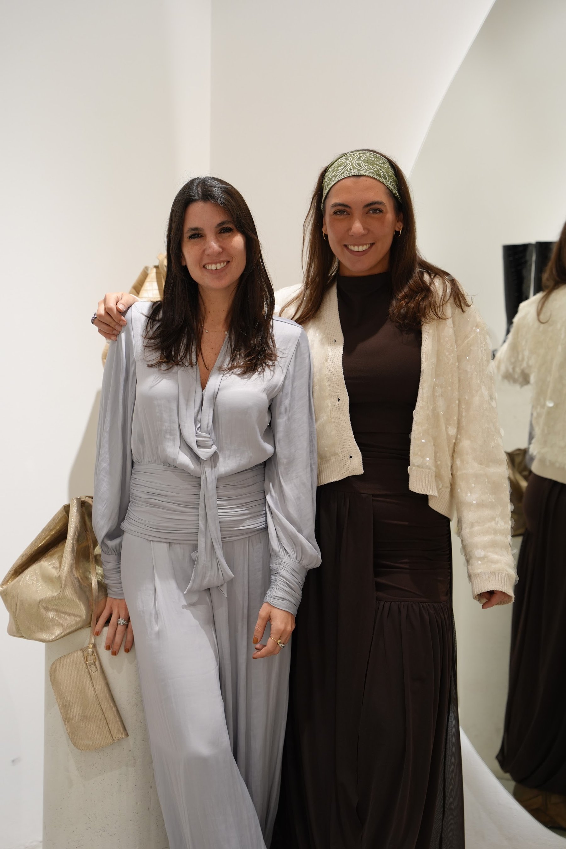 Dos invitadas posando con las bolsas de regalo de la activación.