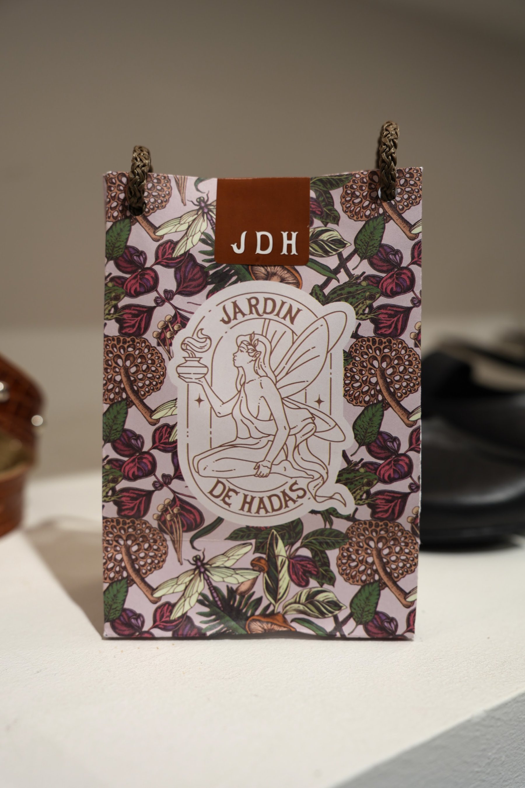 Caja ilustrada de Jardín de Hadas apoyada junto al calzado en exhibición.