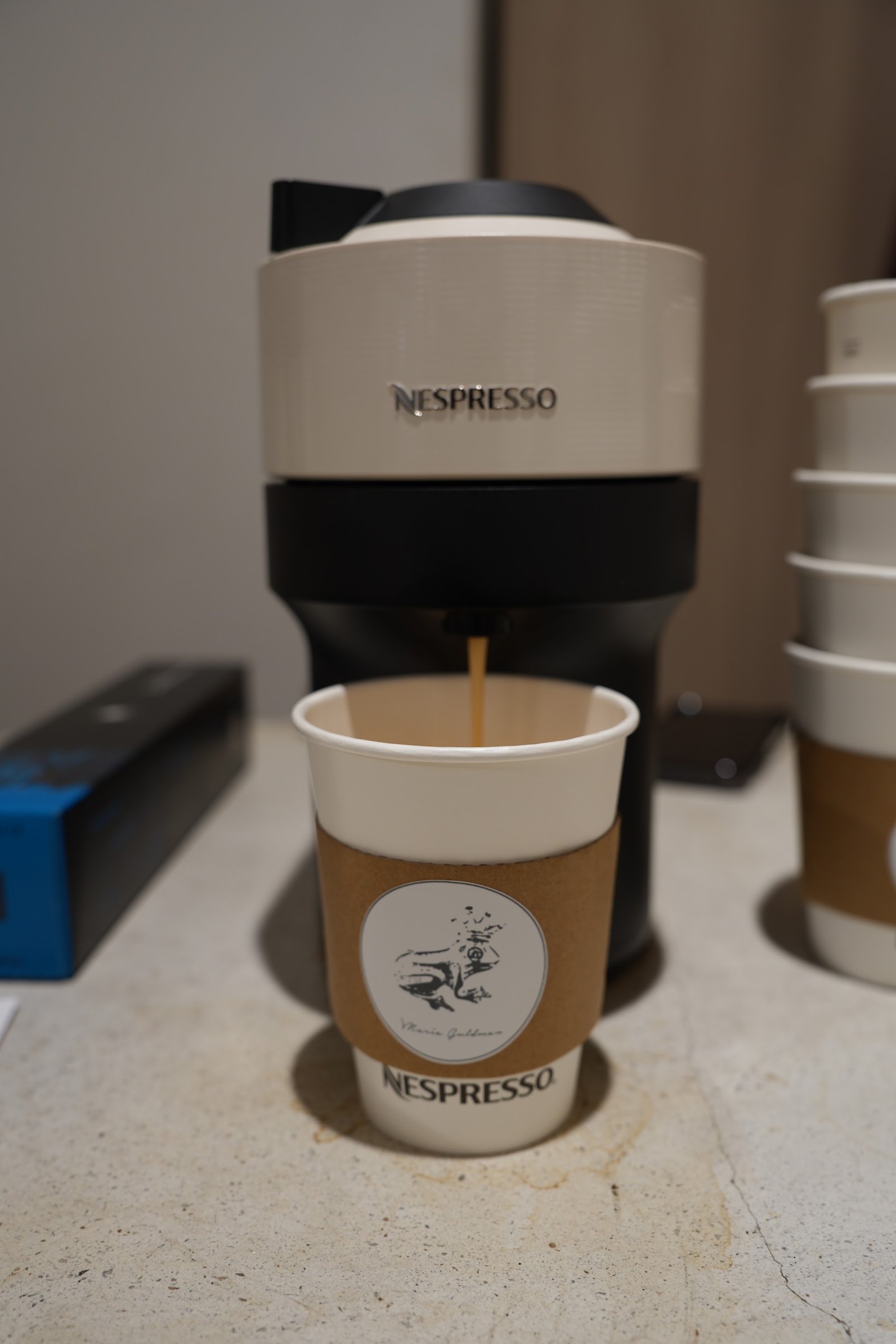 Estación de café Nespresso con la máquina y los vasos de la marca alineados.