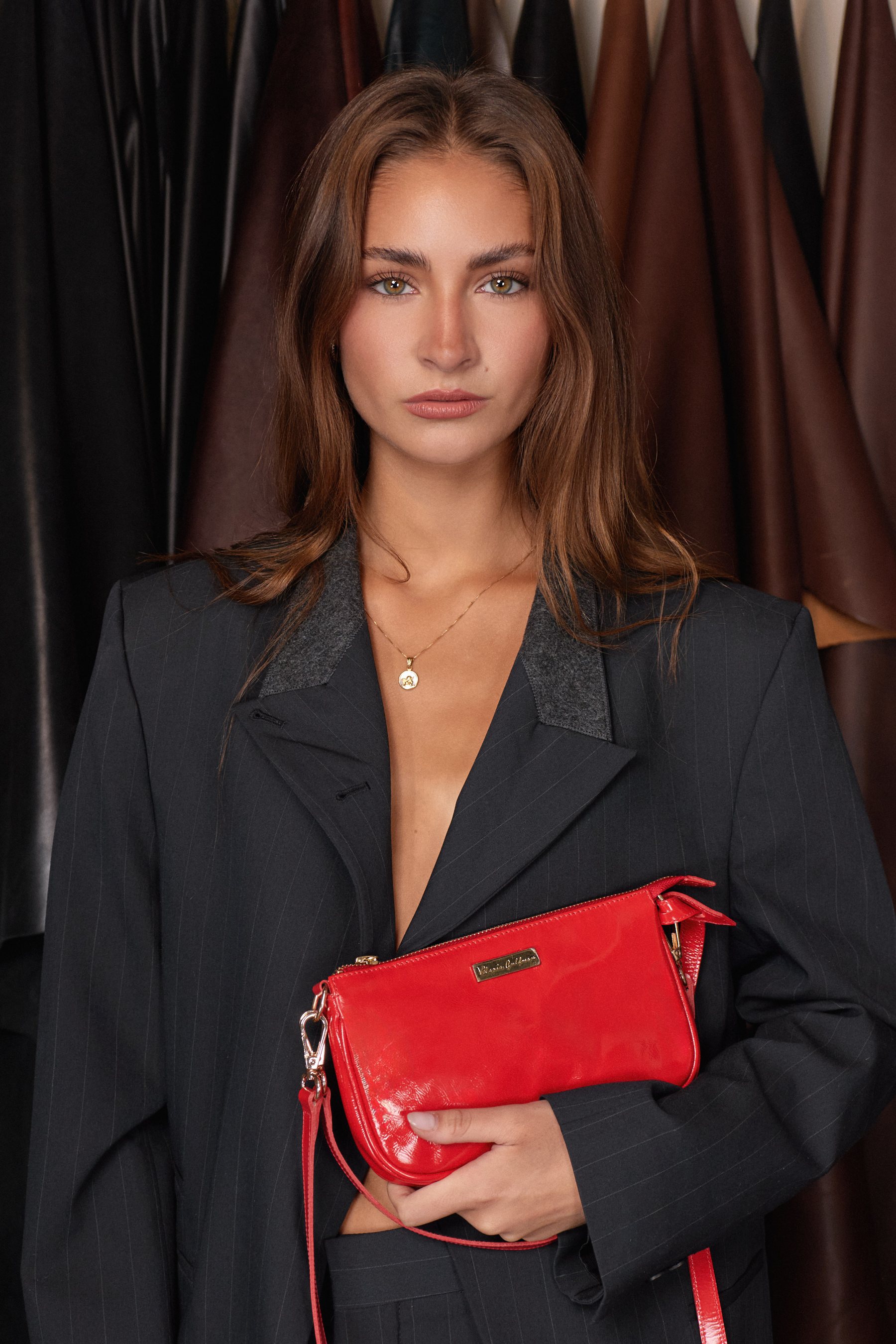 Retrato de modelo con blazer negro oversized y bolso rojo.