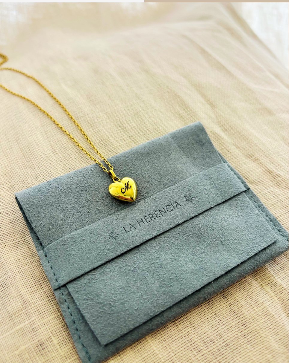 Sobre de entrega con un collar de corazón en oro encima.
