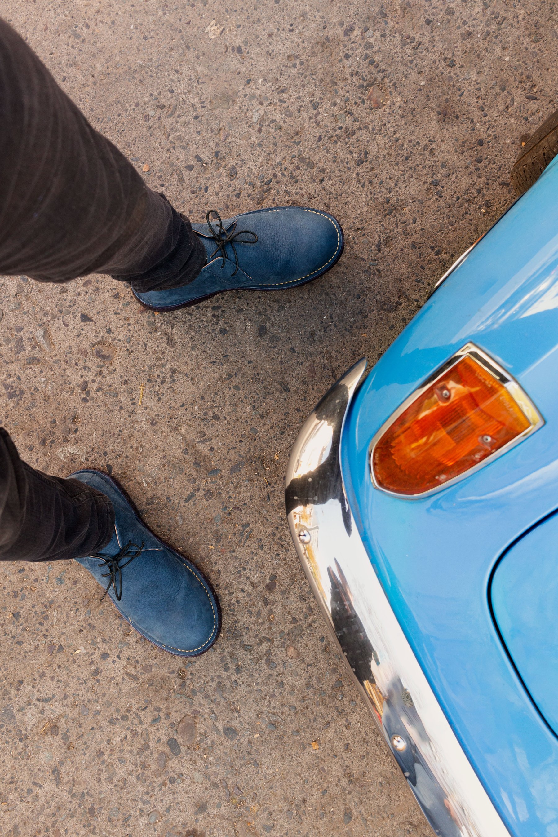 Botas azules junto a la carrocería celeste de un auto.