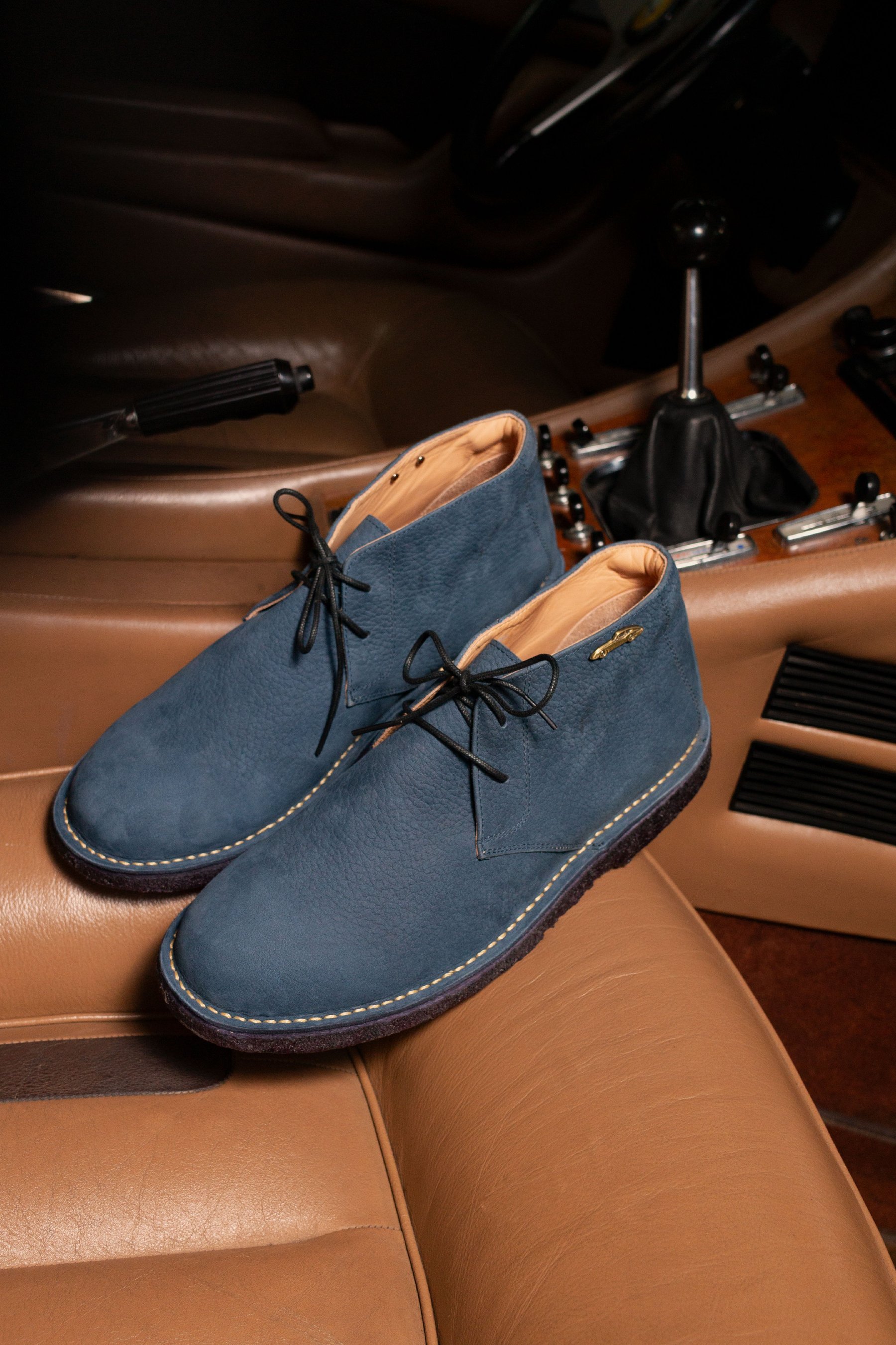 Bota azul apoyada en el interior de cuero de un auto.