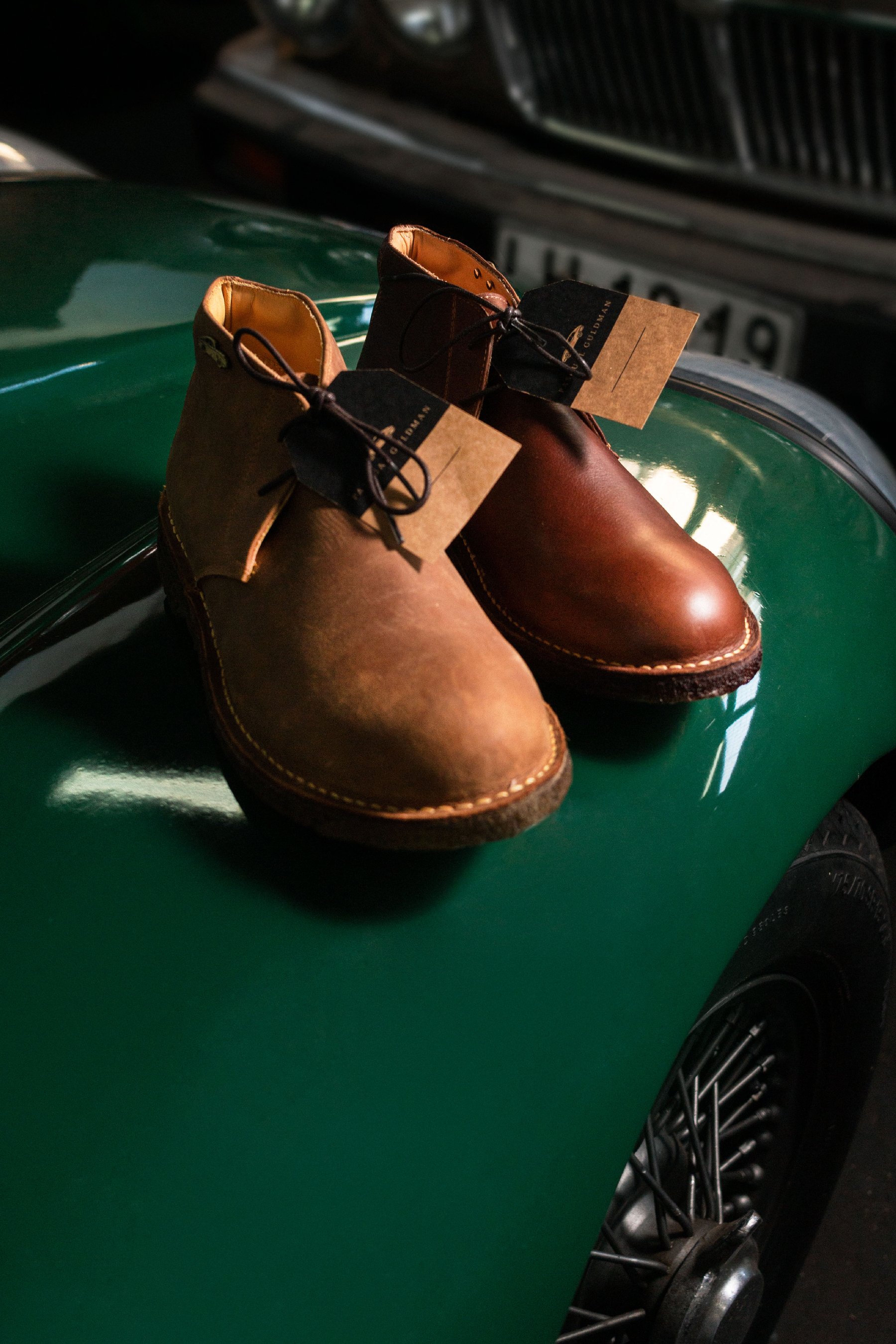 Bota con horma de madera y etiqueta de producto sobre un auto verde.