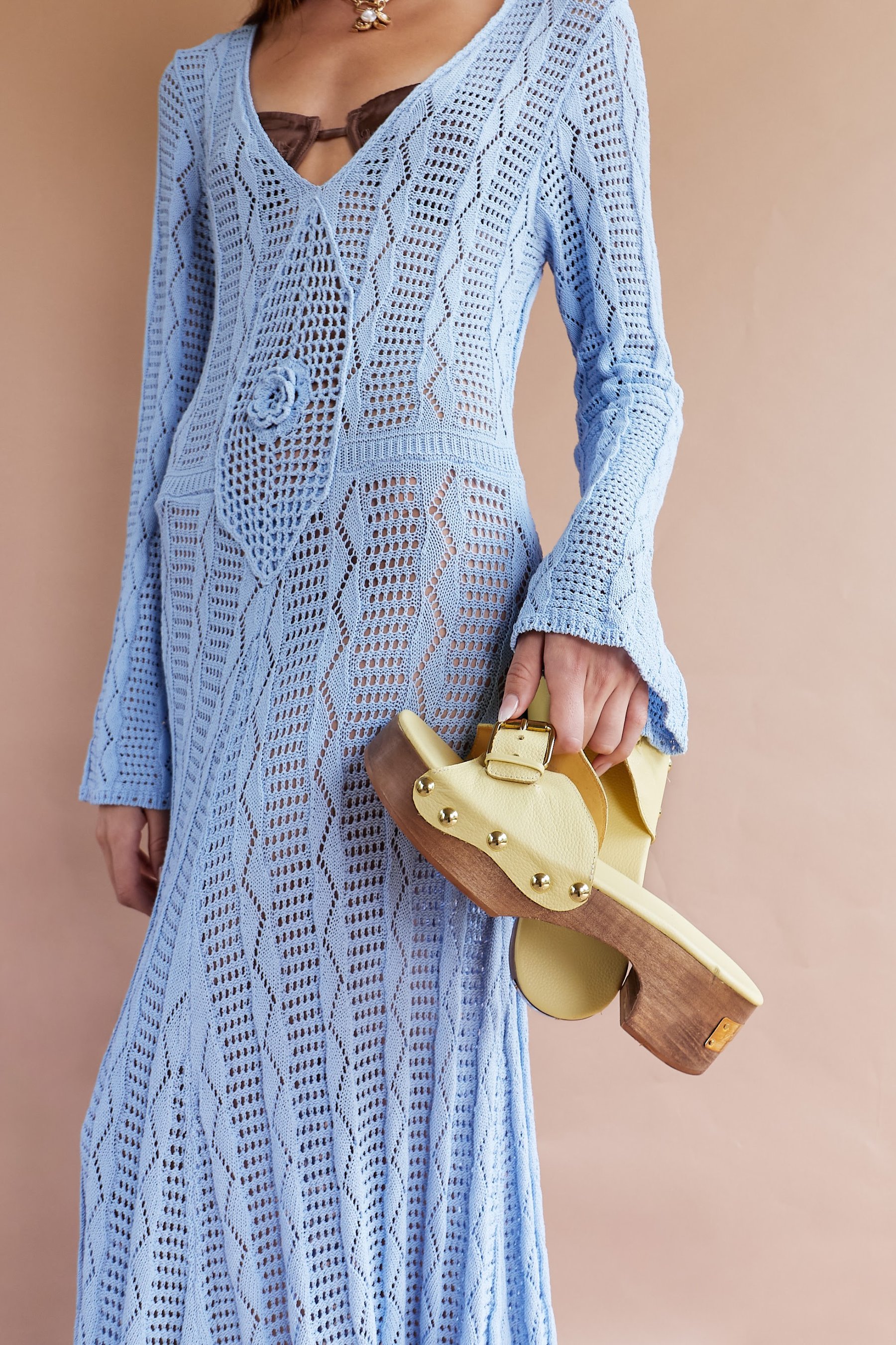 Modelo de pie con vestido de crochet azul y bolso de fibra.