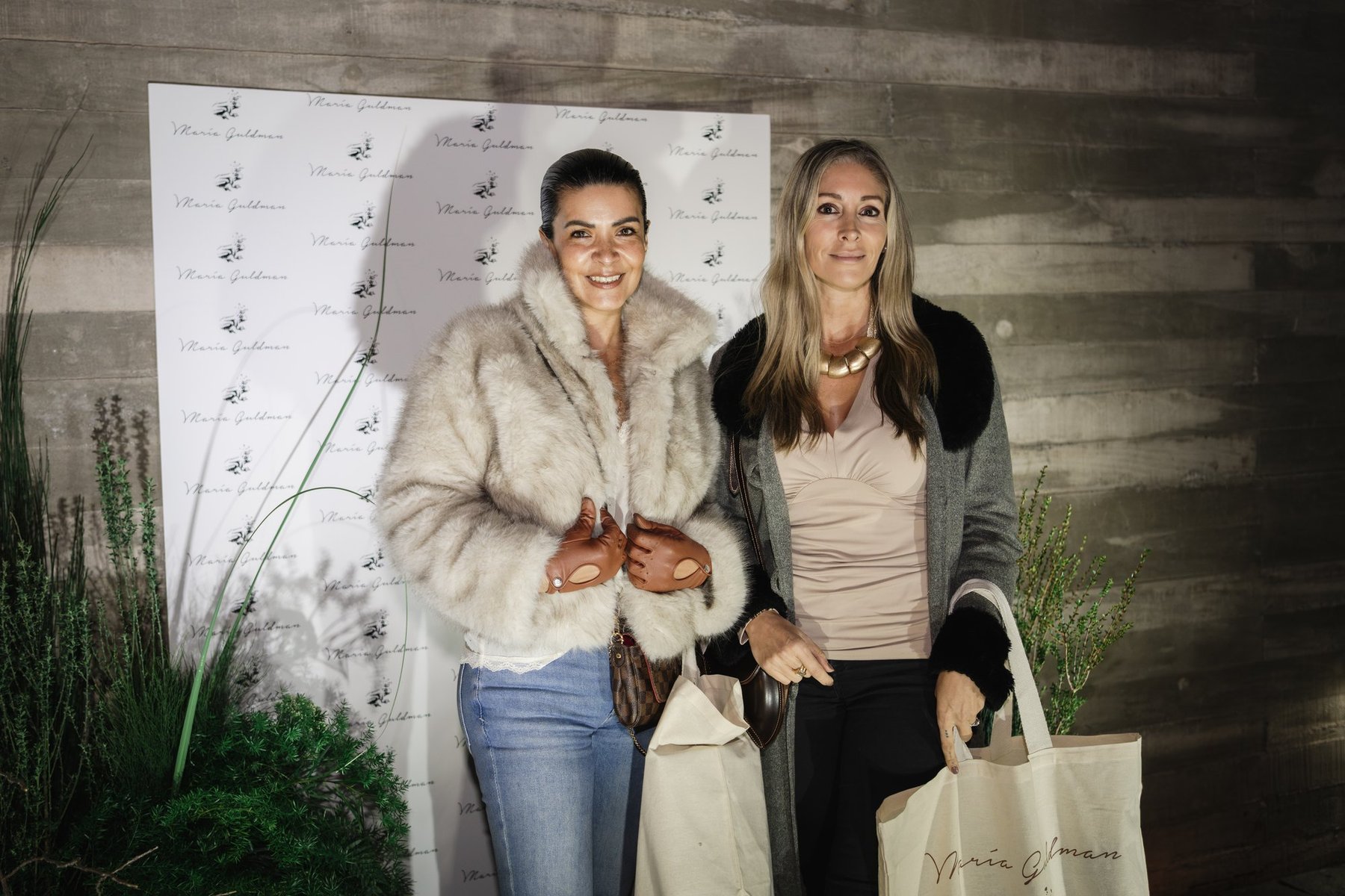 Dos invitadas con las bolsas de regalo del encuentro.
